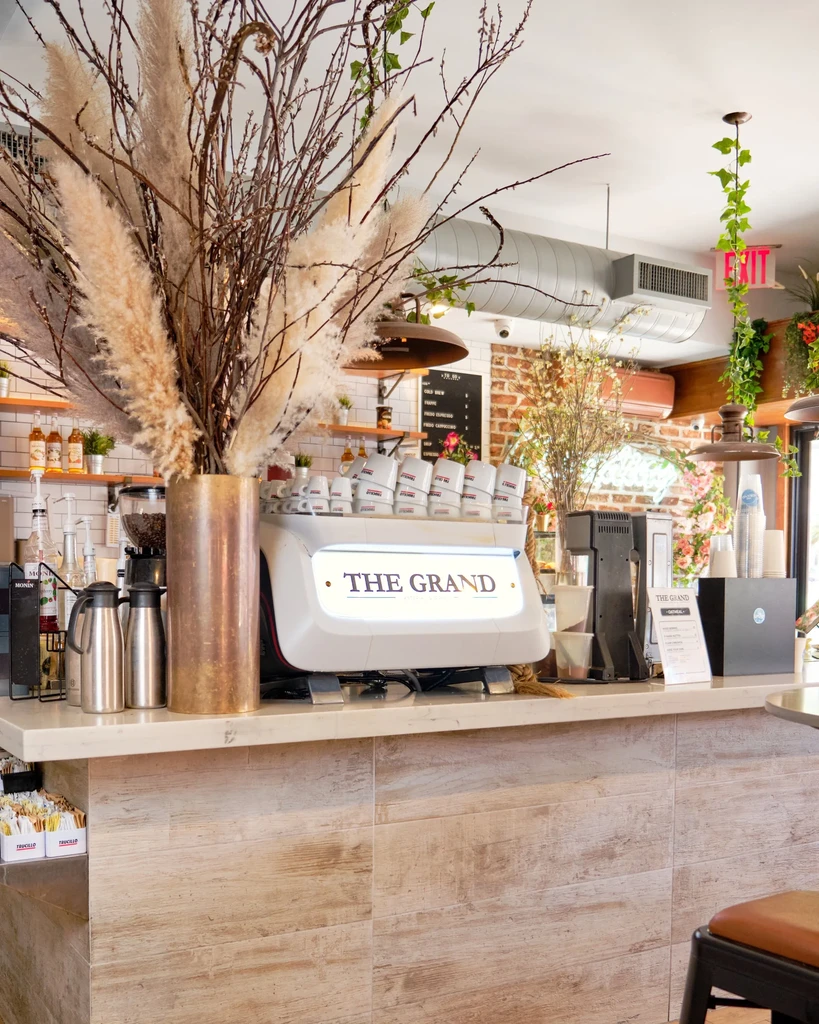 A cafe counter with a large vase of dried pampas grass.
