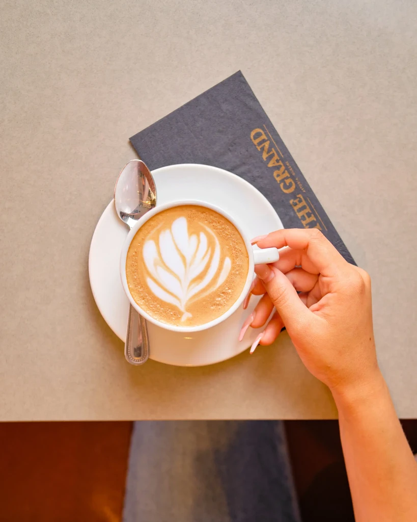 Overhead view of a hand holding a latte with beautiful latte art.