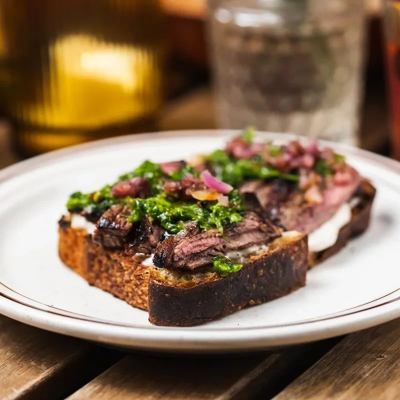 Grilled steak, chimichurri, and pickled onions on toast.