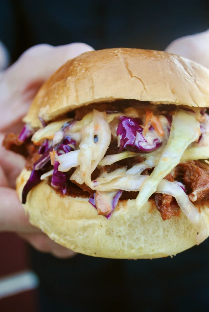 A close-up of a pulled pork sandwich with colorful coleslaw.