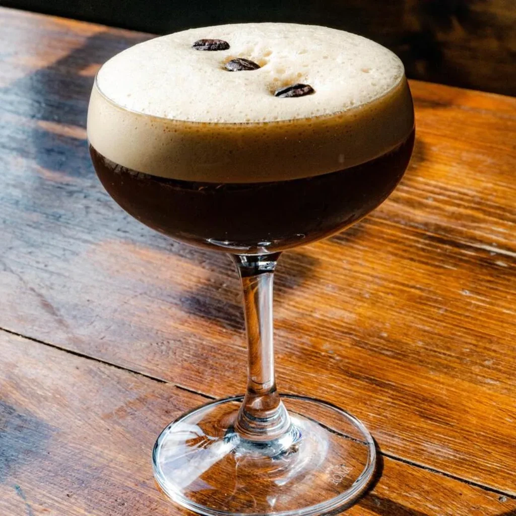 An espresso martini in a coupe glass topped with three coffee beans.