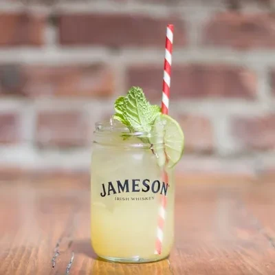 Jameson whiskey cocktail with mint, lime, and a red striped straw.
