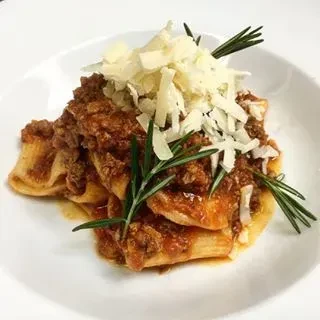 Pasta with rich meat sauce, parmesan cheese, and rosemary sprigs.