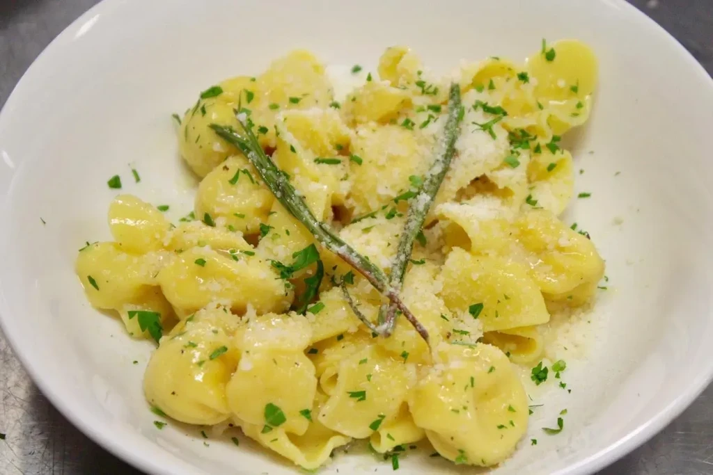 A white bowl of gnocchi pasta, topped with parsley and parmesan.