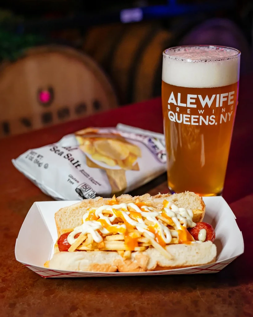 Hot dog with fries, chips, and beer on a table.