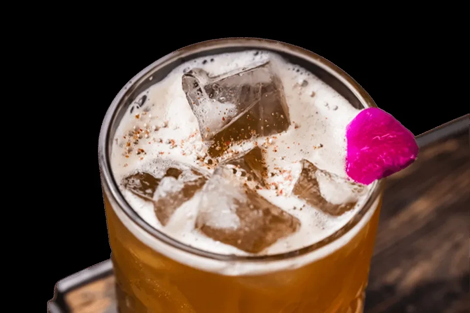 Iced beverage with foam, red spice, and a pink garnish.