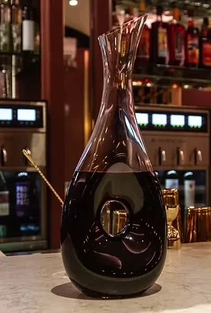 A half-full wine decanter with a unique hole in the side.