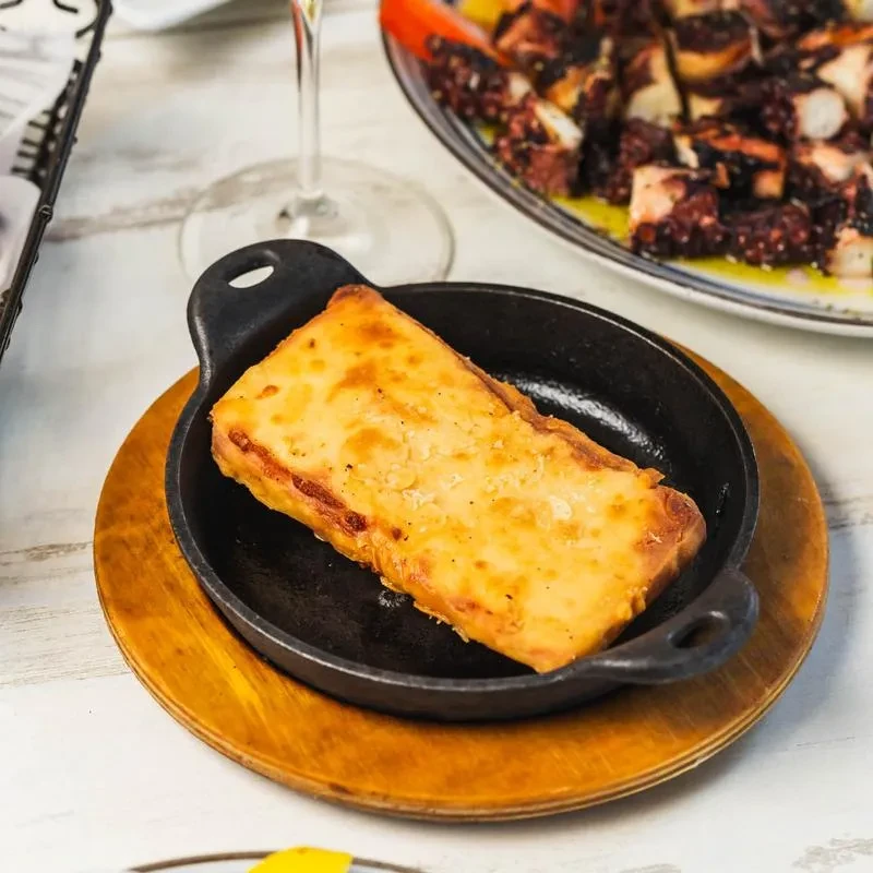 Rectangular golden-brown dish in small black pan on wooden coaster.