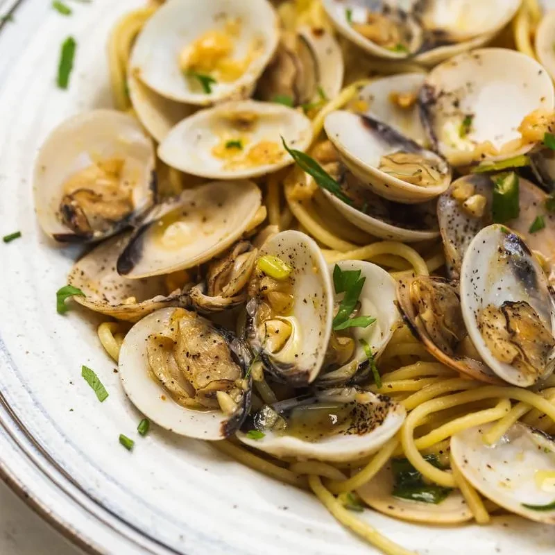 A close-up of spaghetti with clams in a white plate.