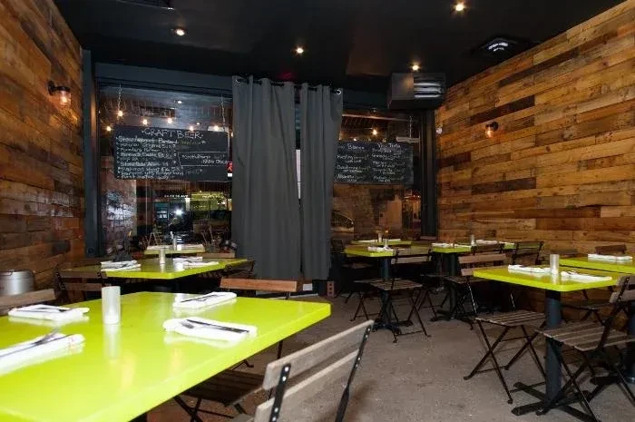 Restaurant interior with wooden walls, green tables, and black chairs.