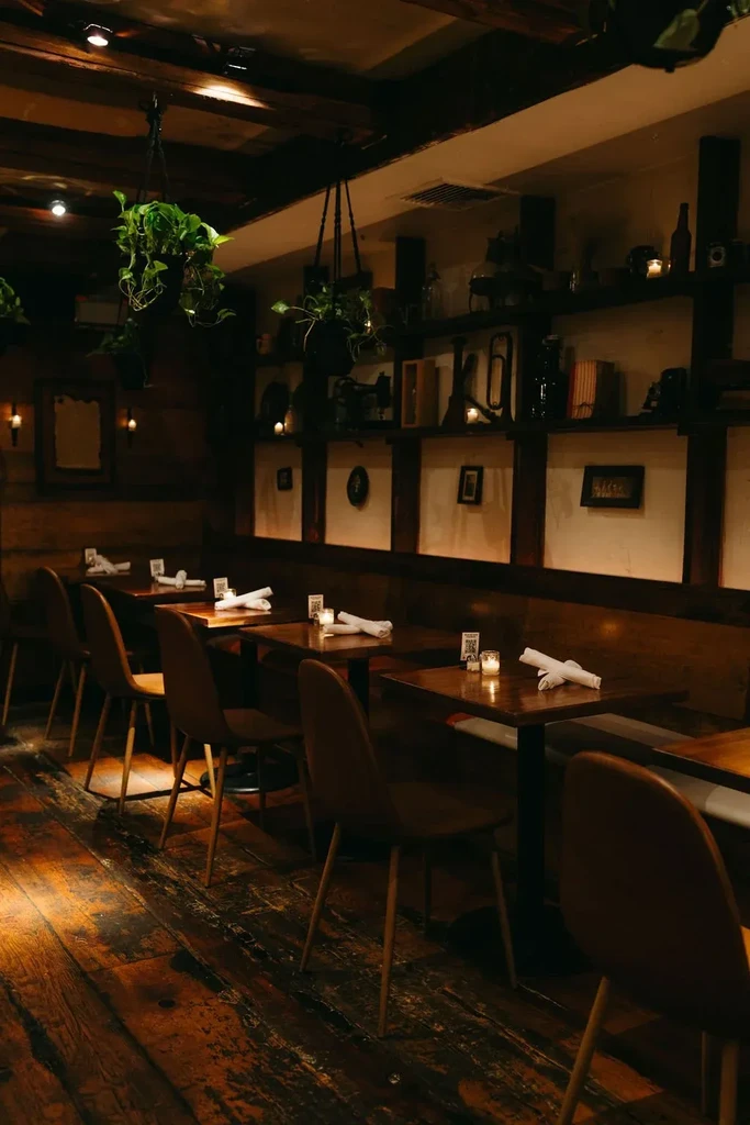 Dimly lit restaurant interior with wooden tables, chairs, and wall decor.