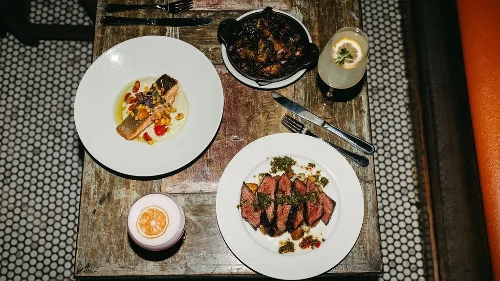 Overhead view of a dining table with two entrees, a side, and two drinks.