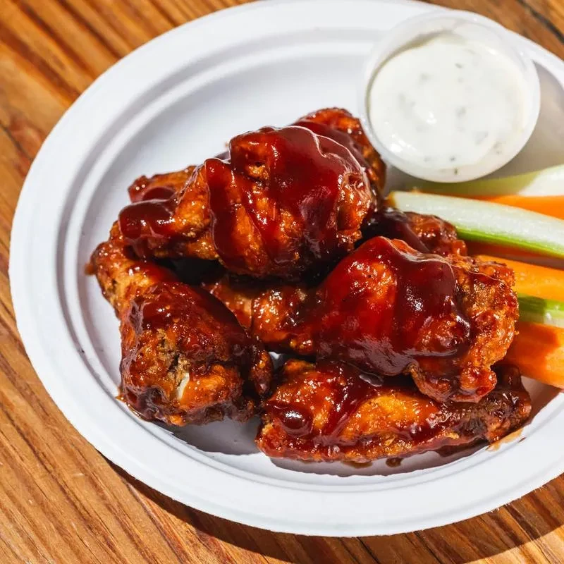 Chicken wings with barbecue sauce, dipping sauce, celery, and carrots.
