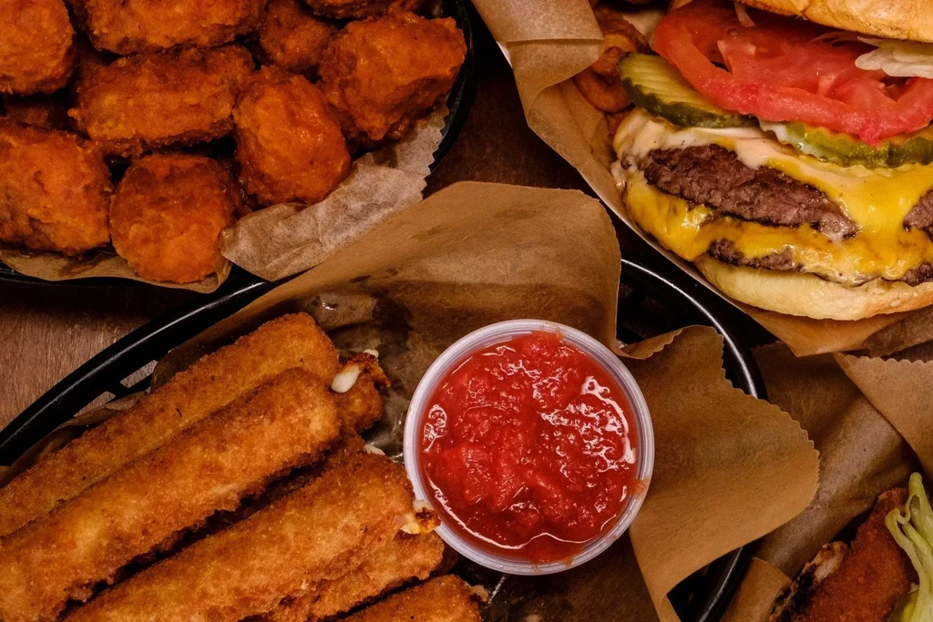 A feast of fried food: wings, mozzarella sticks, and a cheeseburger.