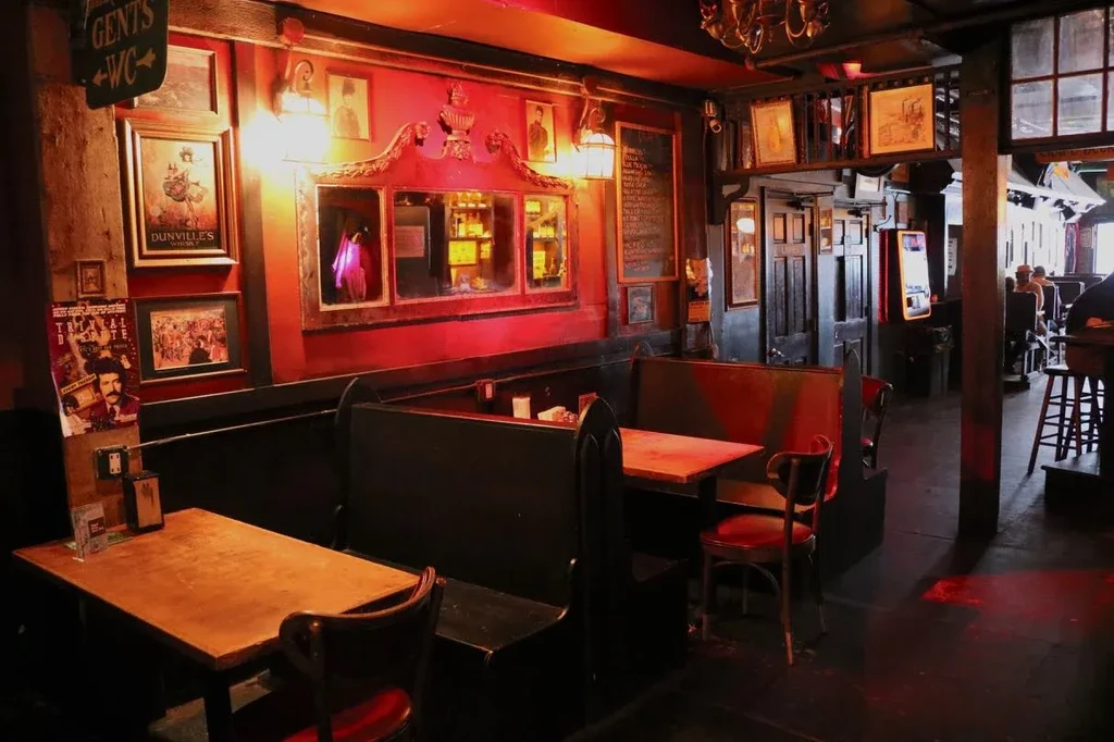 Interior of a dimly lit pub with red walls and wooden tables.