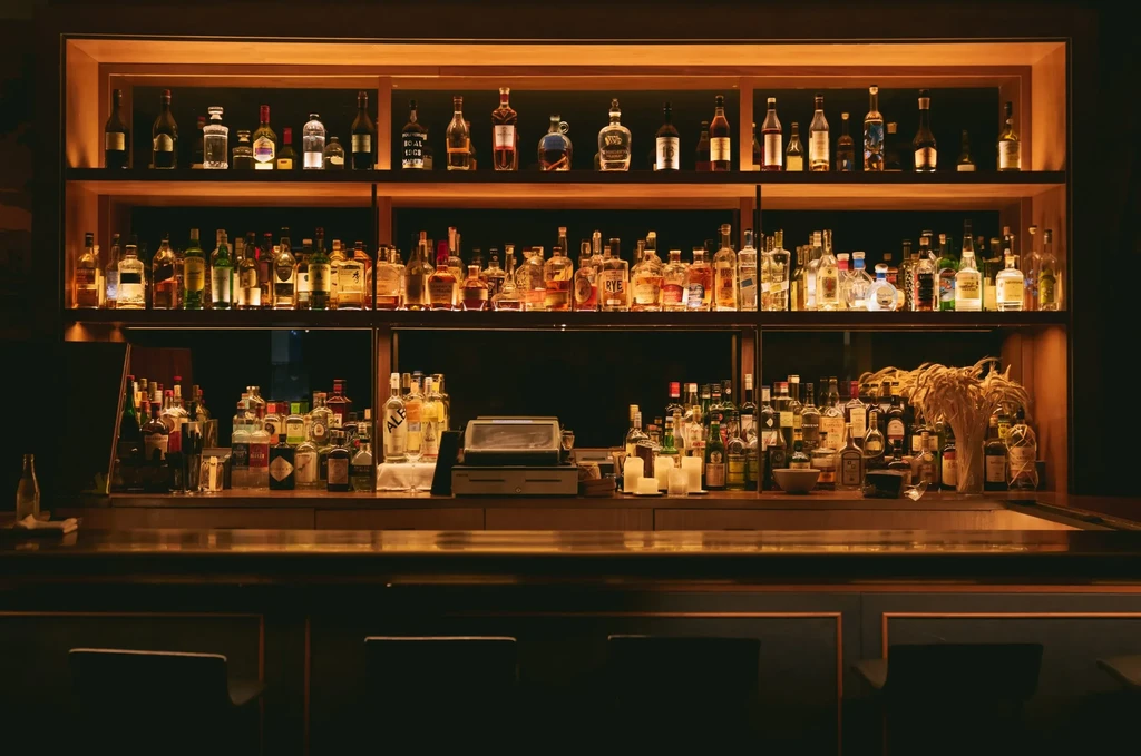 An illuminated bar showing various bottles of liquor on shelves.