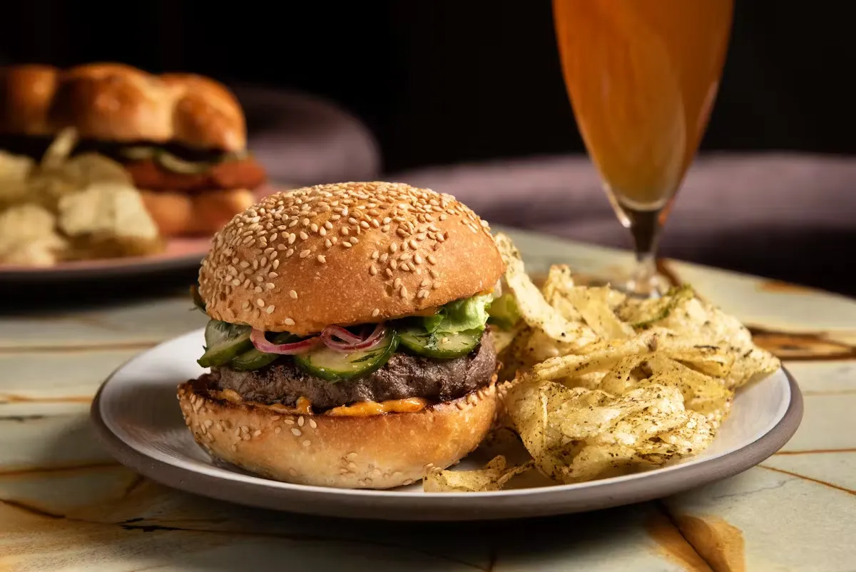 Burger with potato chips and a drink on a table.
