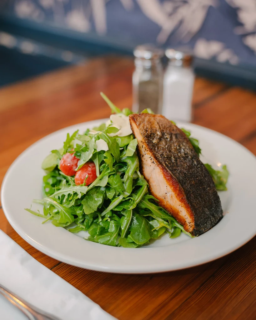 Pan-seared salmon with a side of arugula and cherry tomato salad.