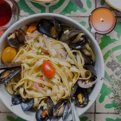 Bowl of tagliatelle pasta with mussels, clams, and cherry tomatoes.