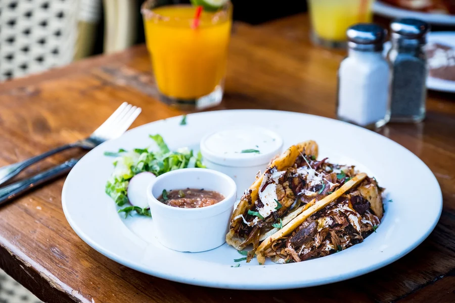 Crispy tacos with shredded meat, salad, and sauces.