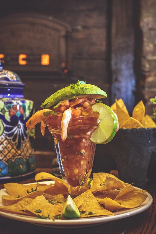 Shrimp cocktail in a glass with lime, avocado, and tortilla chips.