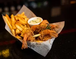 Fried shrimp and french fries with dipping sauce and lemon.