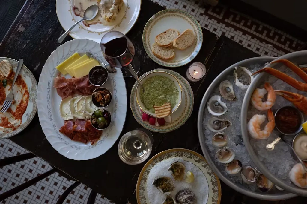 A table set with charcuterie, oysters, seafood, and wine.