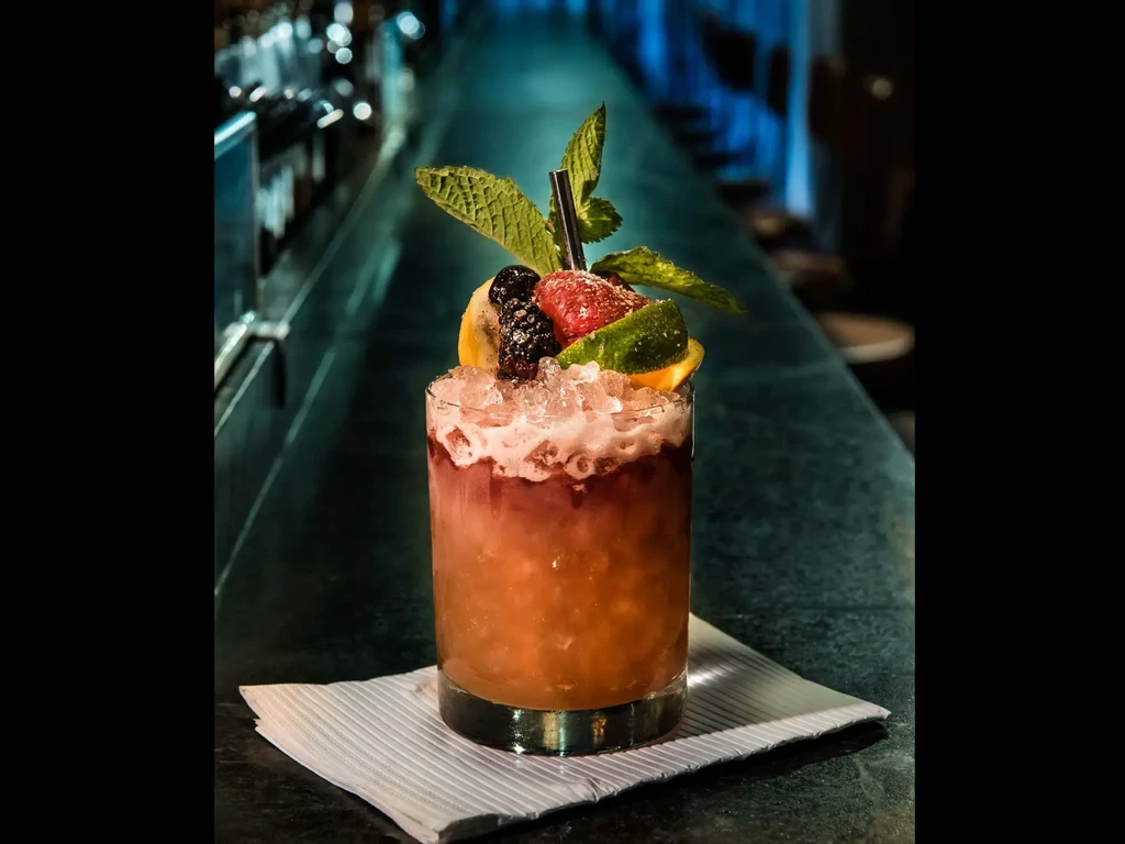 A colorful fruit cocktail with mint on a bar counter.