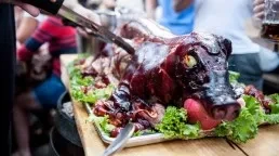 A roasted pig with an apple in its mouth on a platter.