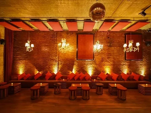 A dim, upscale lounge with red cushions and a disco ball.