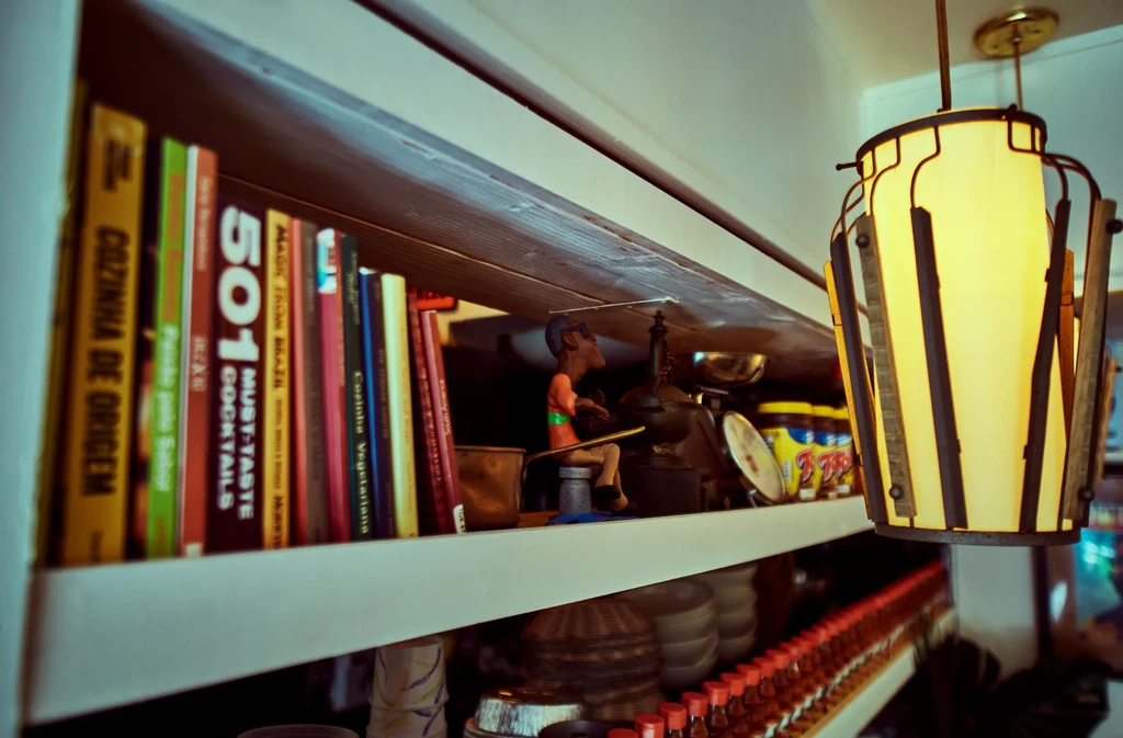 A bookshelf filled with books and a figurine, with a hanging lamp.