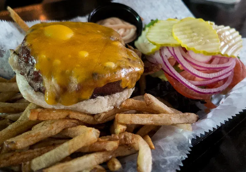 A cheeseburger with toppings, a side of fries, and dipping sauce.