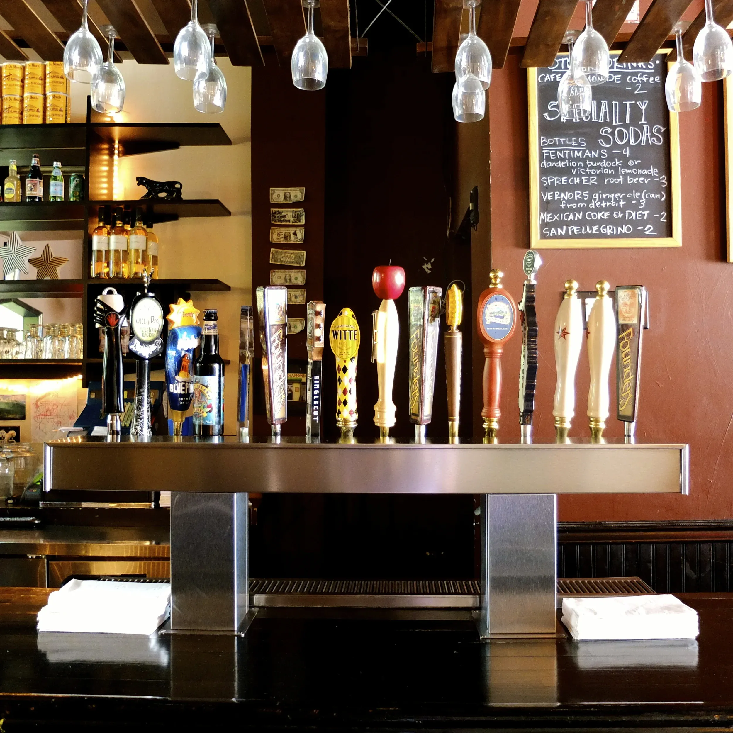 A bar with beer taps, wine glasses, and a specialty soda menu.