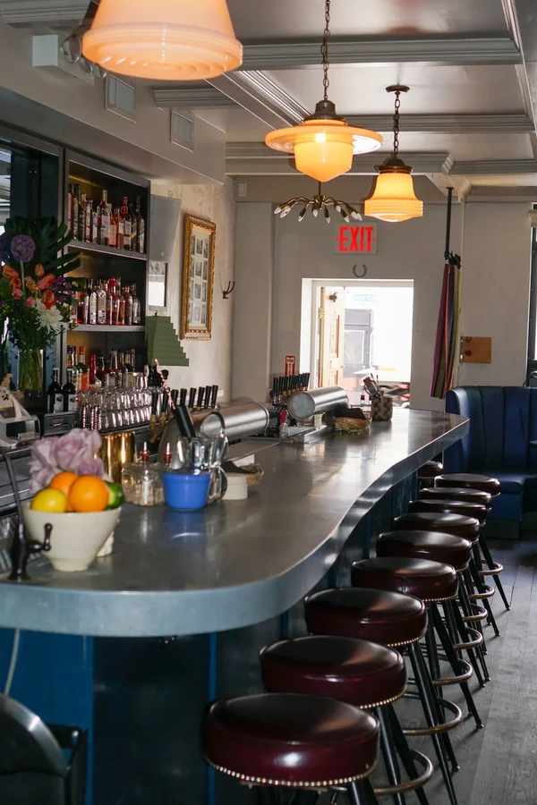 A long, curving bar with stools and overhead lights in a restaurant.