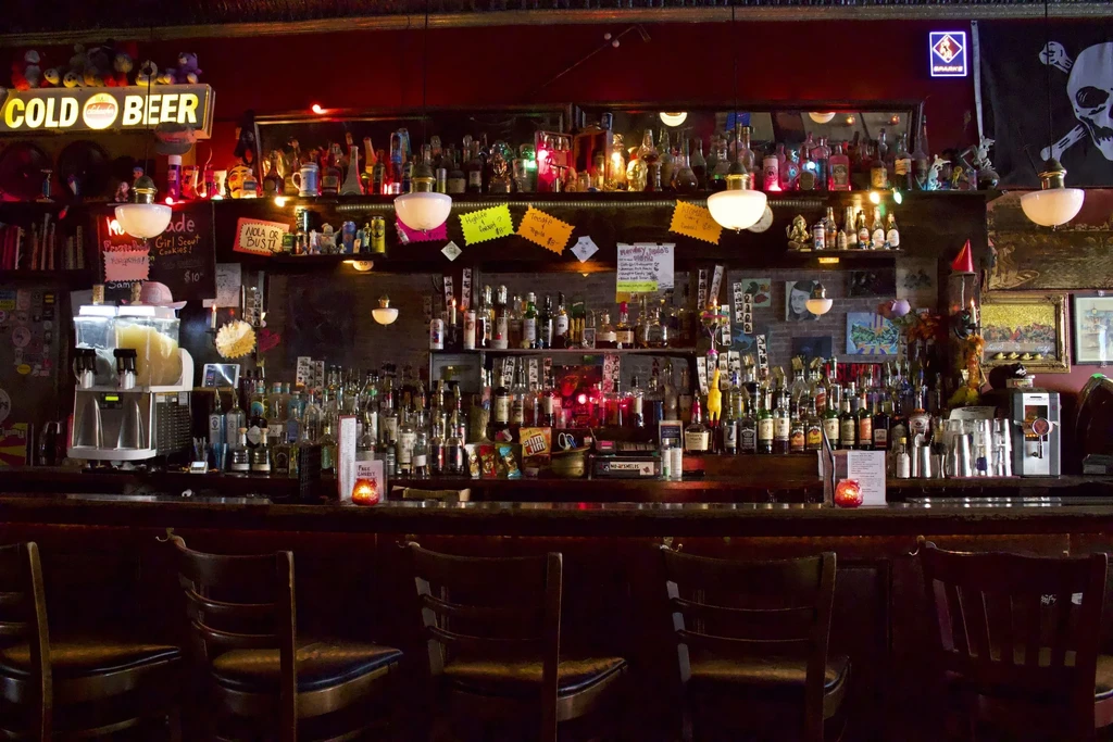 A bar with shelves of liquor bottles and bar stools.