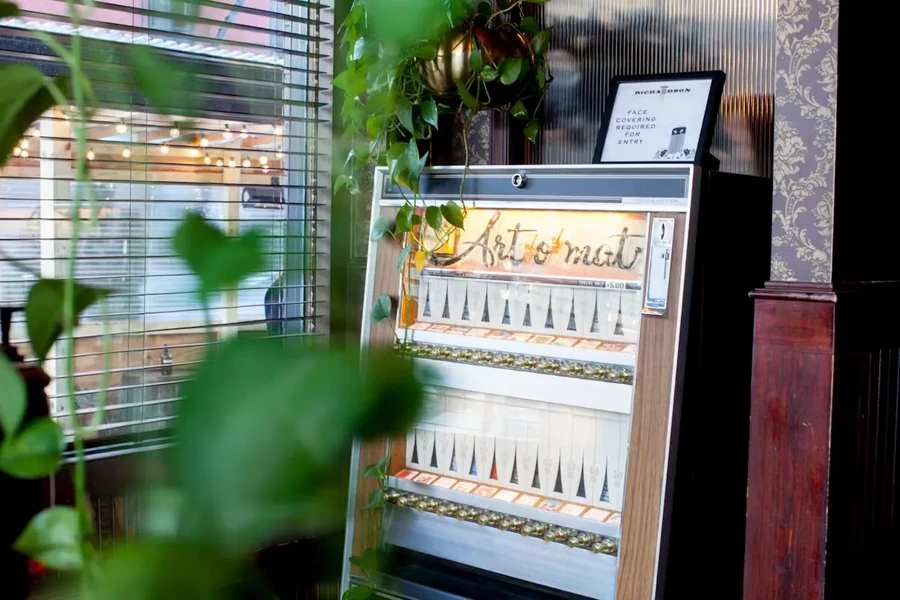 Art-o-mat machine full of small artworks next to a window.