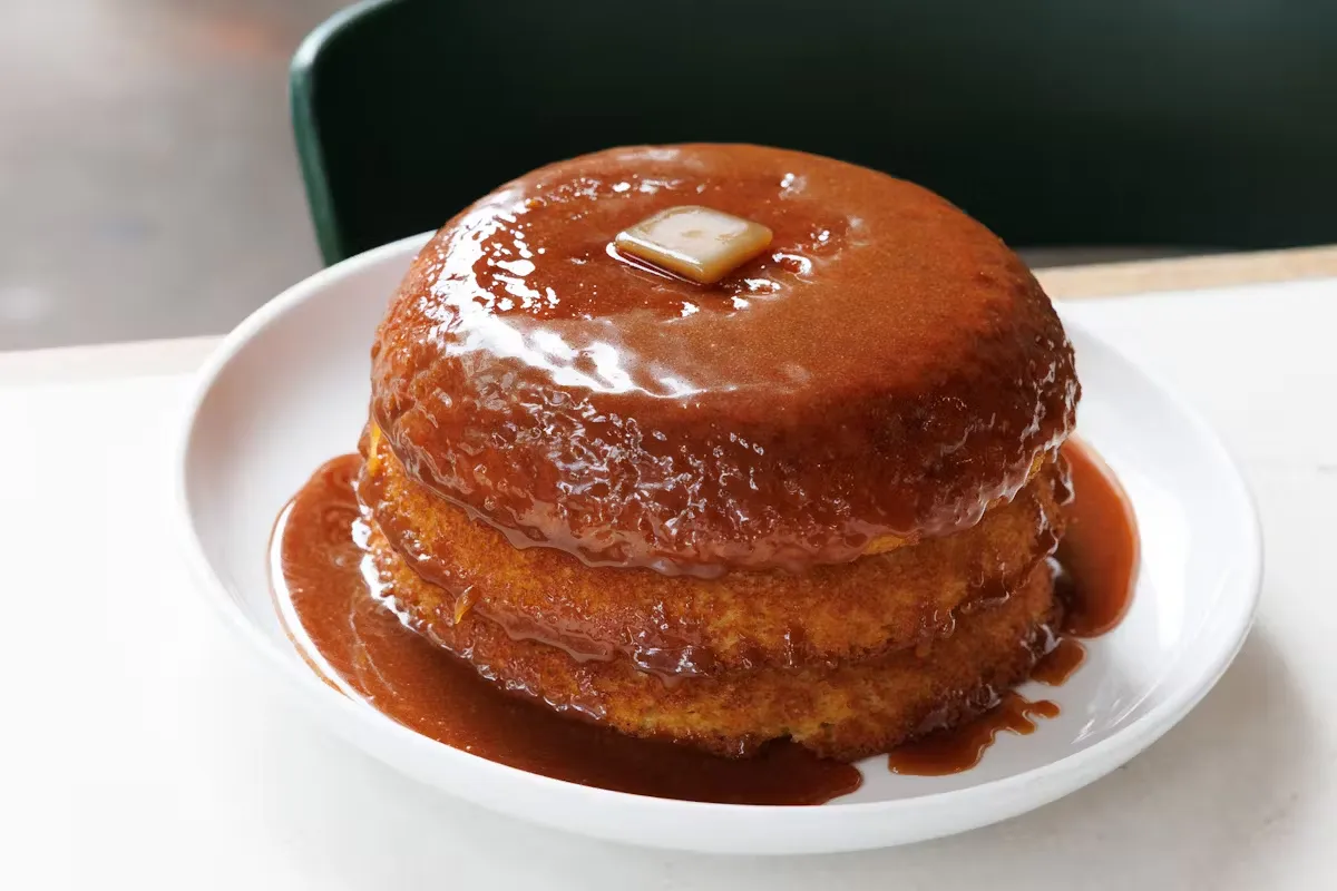 A stack of pancakes topped with syrup and a pat of butter.