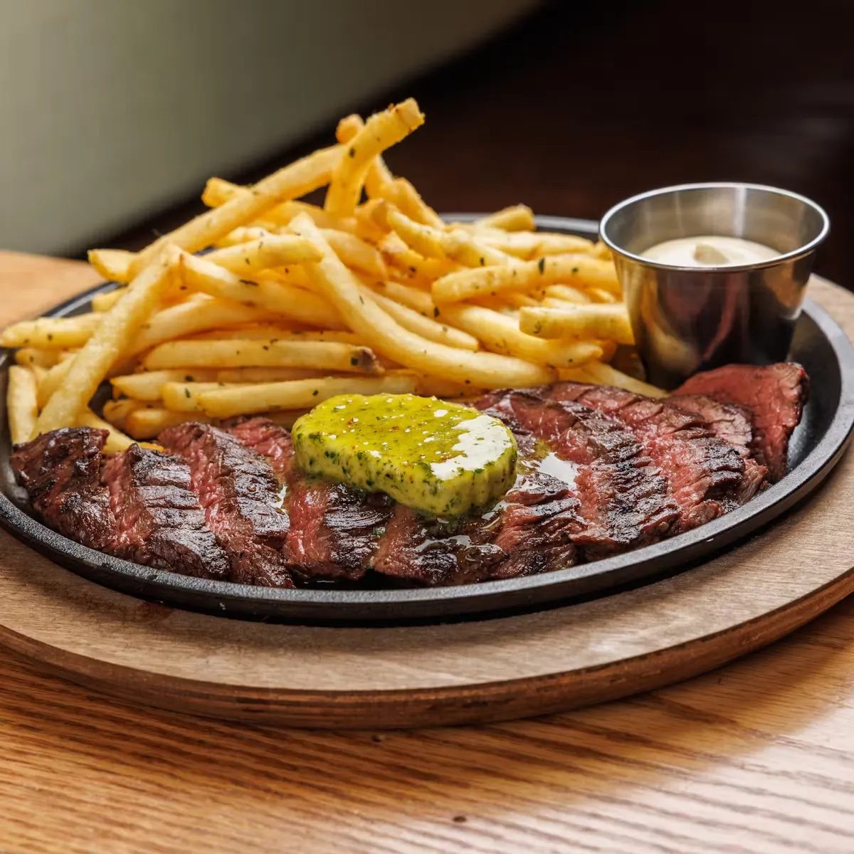 Sliced steak with herbed butter, french fries, and dipping sauce.