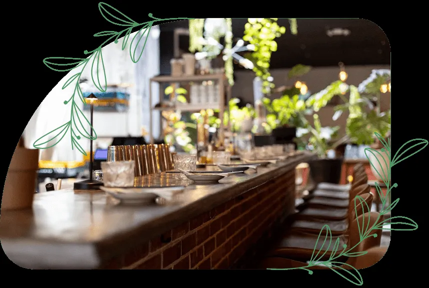 A bar with brick base, glasses, plates, and plants inside.