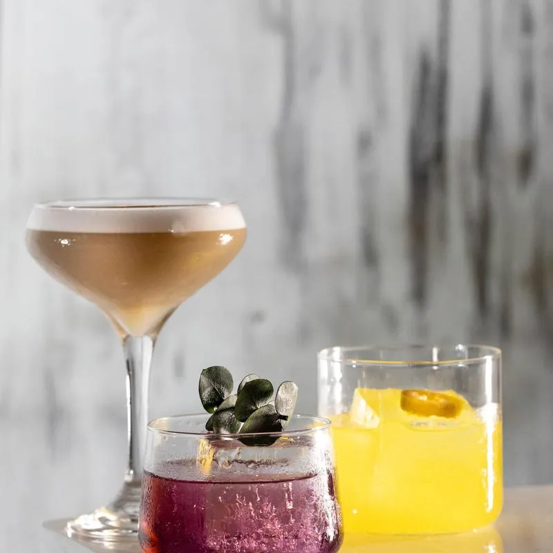 Three different cocktails in clear glasses against a grey background.