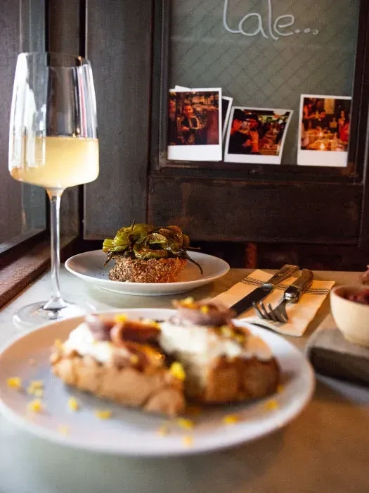 Pintxos and wine are served at a restaurant with photos on the wall.