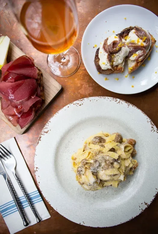 Overhead shot of an Italian meal with wine on a copper table.