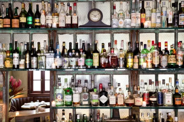 Multiple shelves of liquor bottles on display behind a bar.