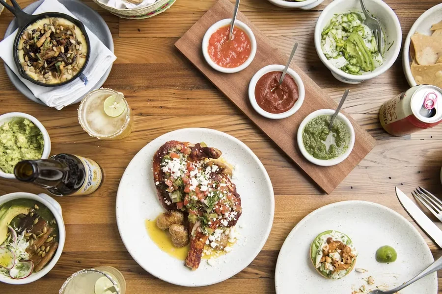 An overhead shot of a wooden table with many Mexican dishes.