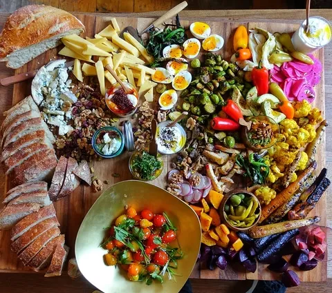 Colorful grazing board with cheeses, bread, vegetables, and other foods.