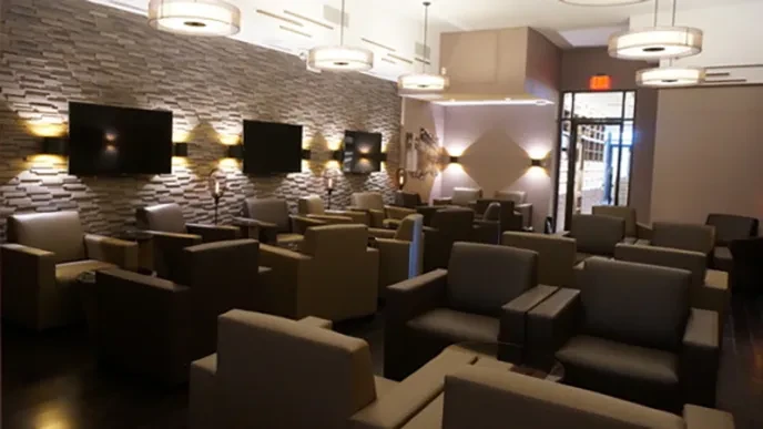 An empty modern lounge area with rows of armchairs and televisions.
