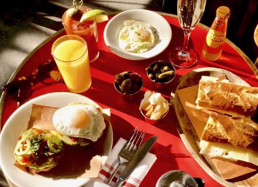 A sunny table with breakfast items, drinks, and snacks on a red table.