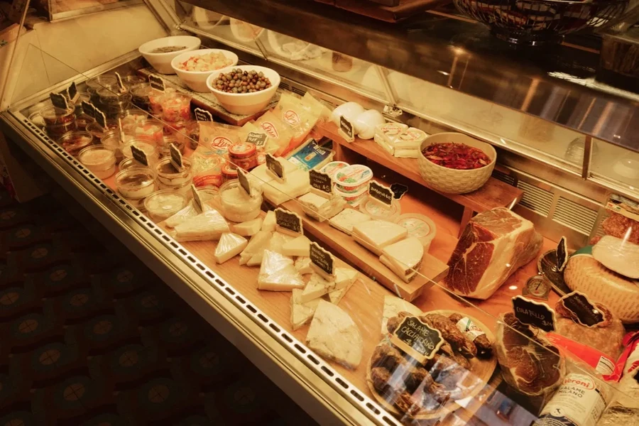 A deli display case filled with cheeses, meats, and other foods.