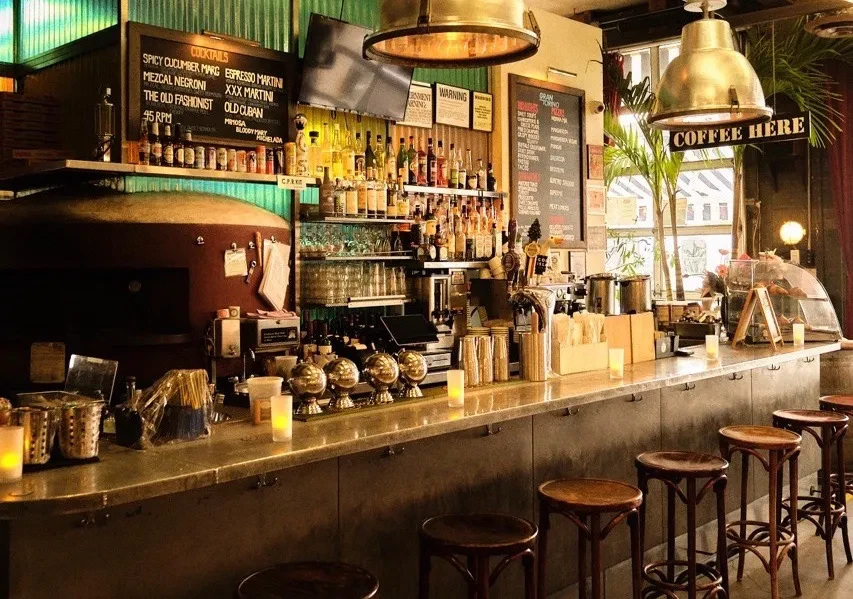 A rustic bar interior with a long counter and many bottles of alcohol.