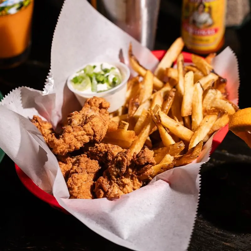 Fried chicken tenders, french fries, and a cup of dipping sauce.